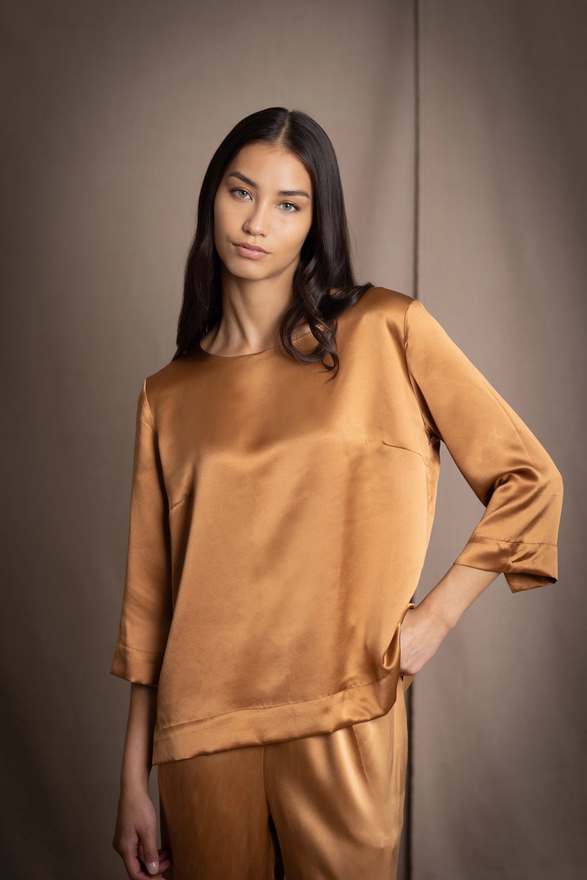 woman wearing a bronze silk 3/4 sleeve top blouse with matching silk trousers