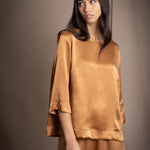 woman wearing a bronze silk 3/4 sleeve top blouse with matching silk trousers