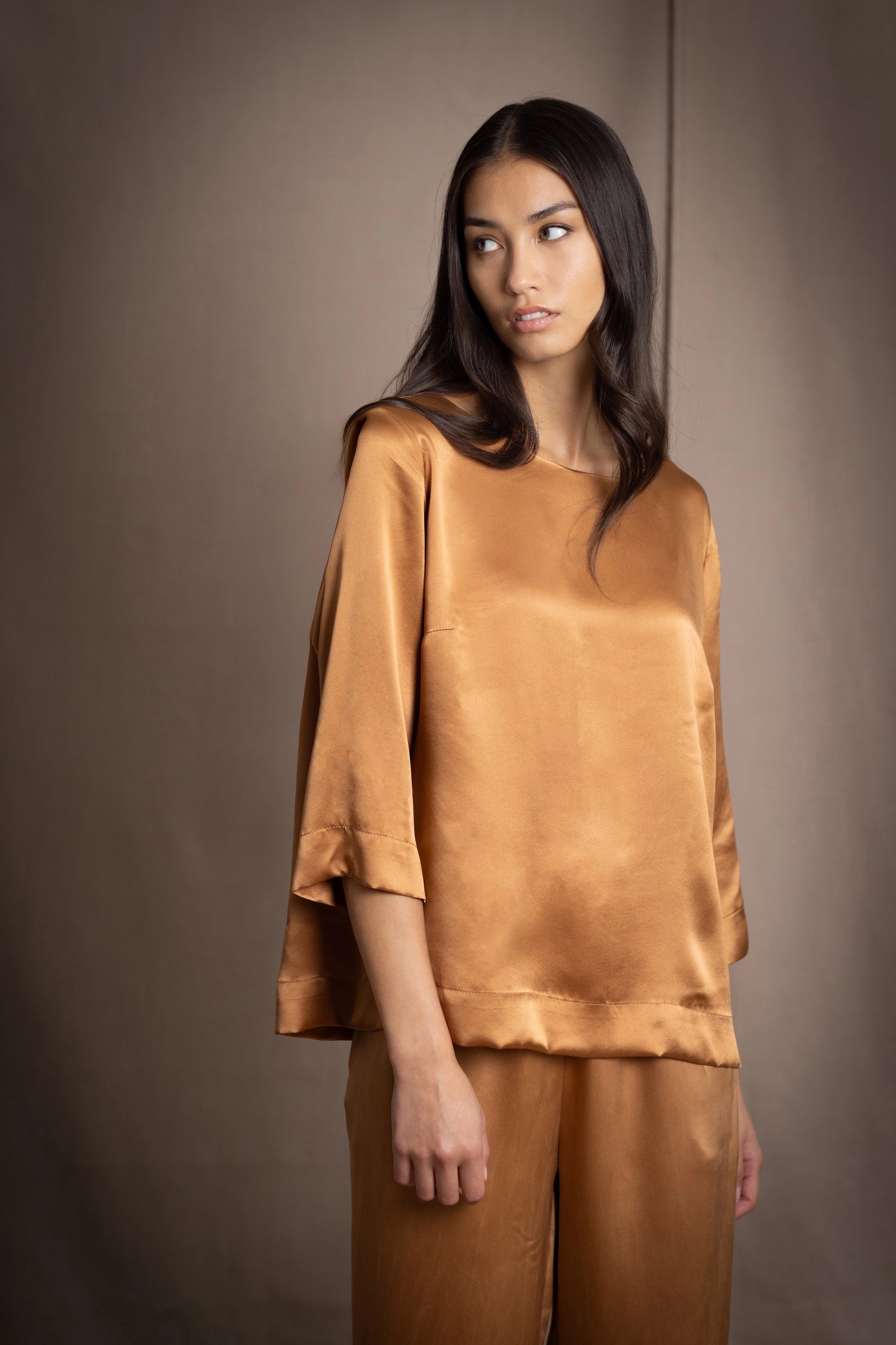 woman wearing a bronze silk 3/4 sleeve top blouse with matching silk trousers