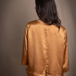 woman wearing a bronze silk 3/4 sleeve top blouse with matching silk trousers