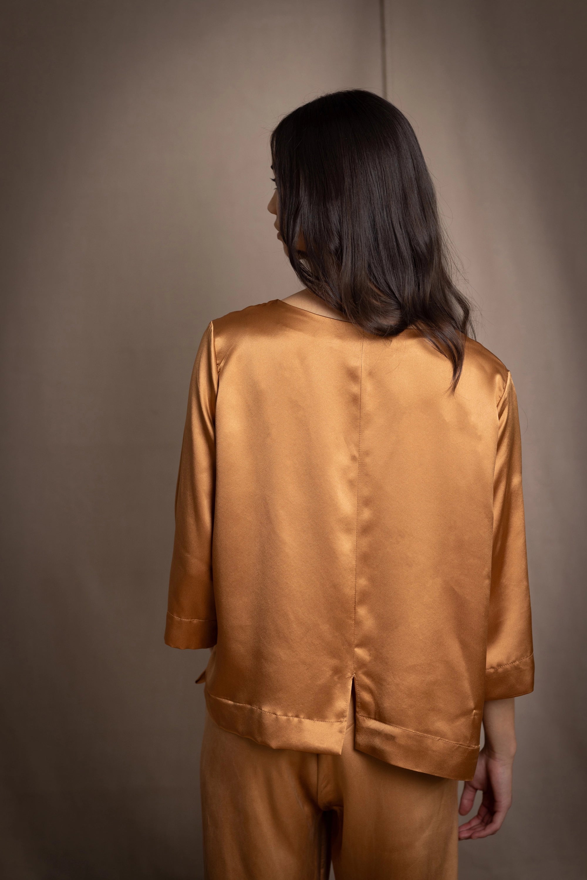woman wearing a bronze silk 3/4 sleeve top blouse with matching silk trousers