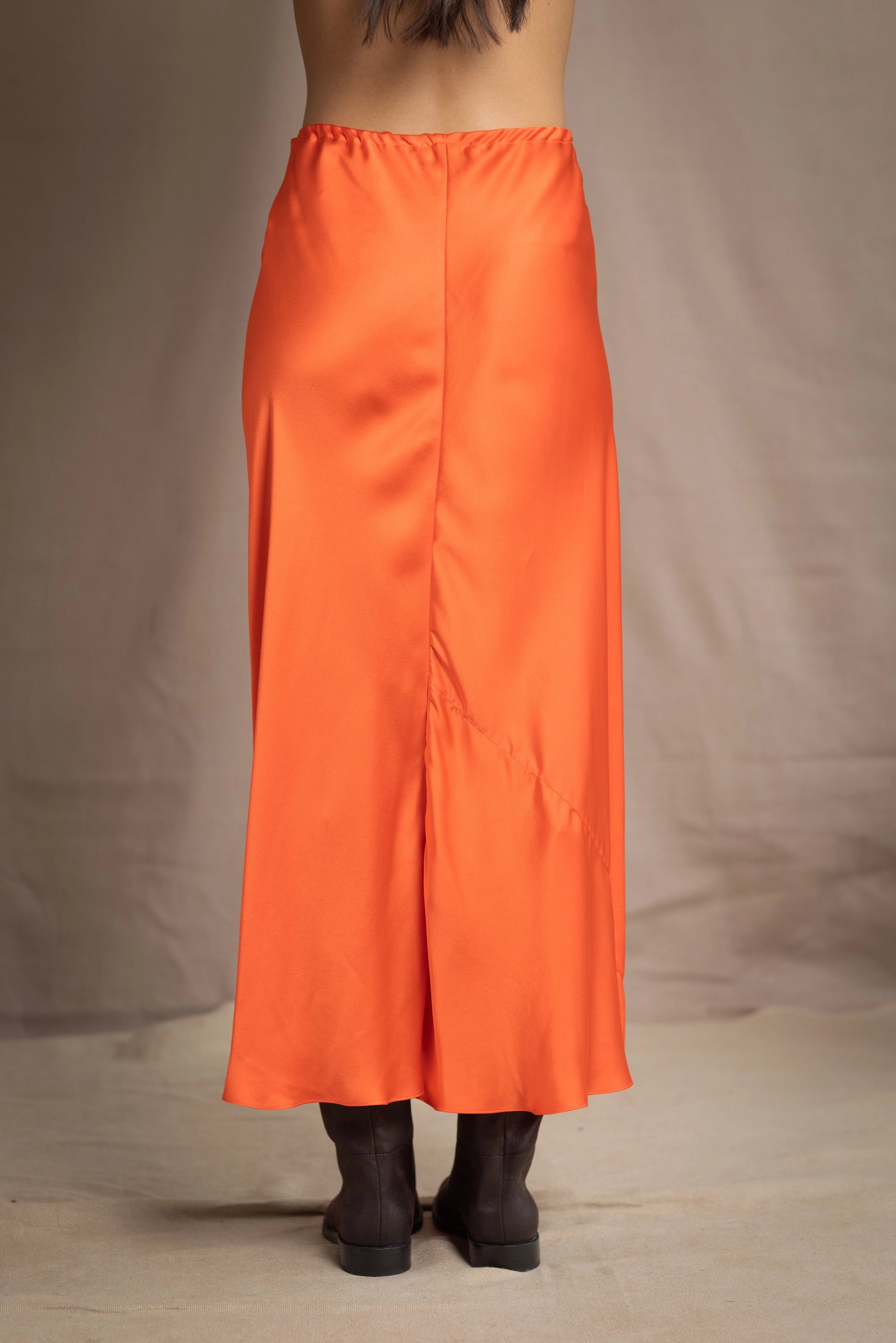 a woman wears a silk skirt in orange