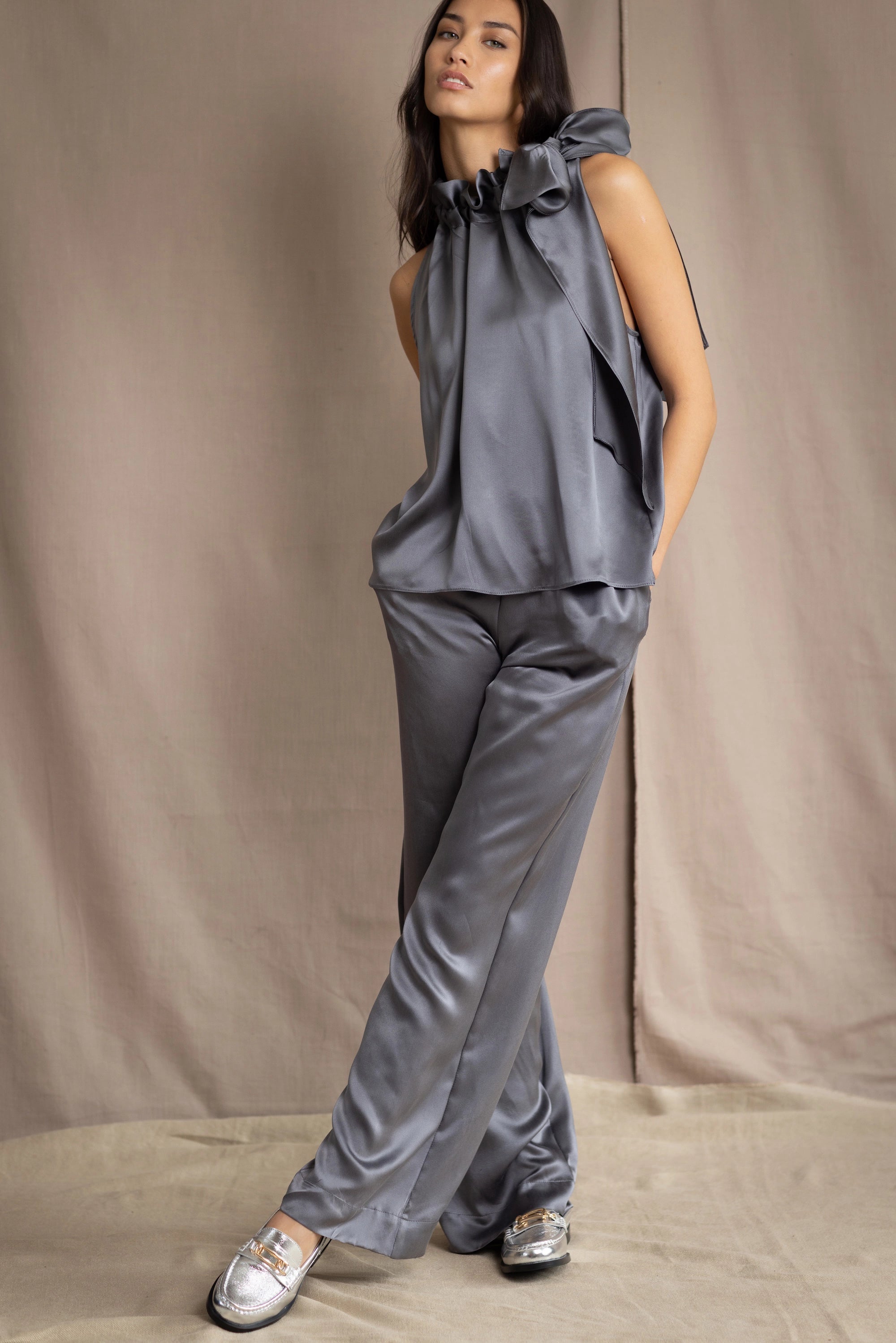 Woman wearing a gray sleeveless silk top and silk pants