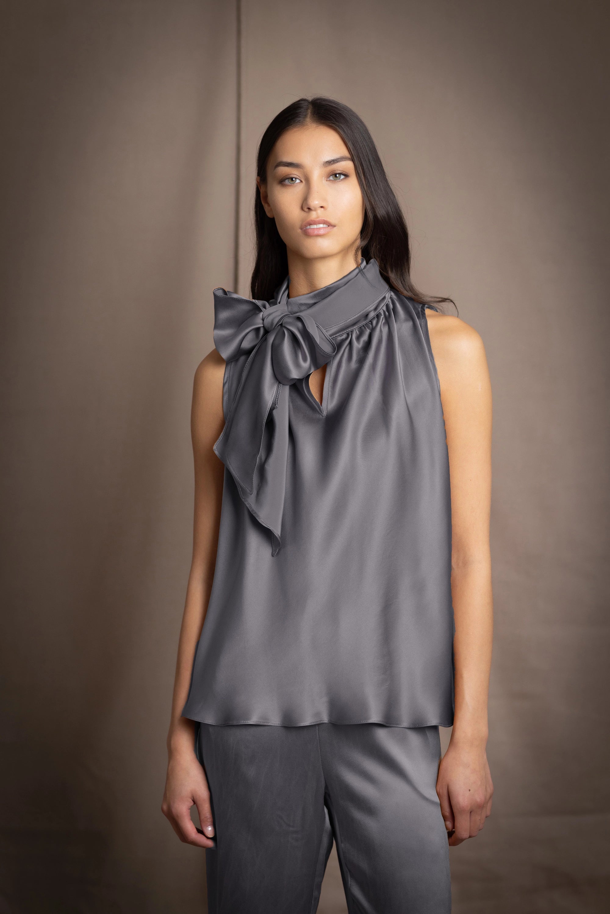Woman wearing a dark gray pussy bow silk blouse with matching trousers