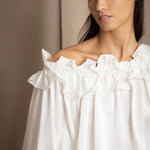 Woman wearing a white silk blouse with ruffled details