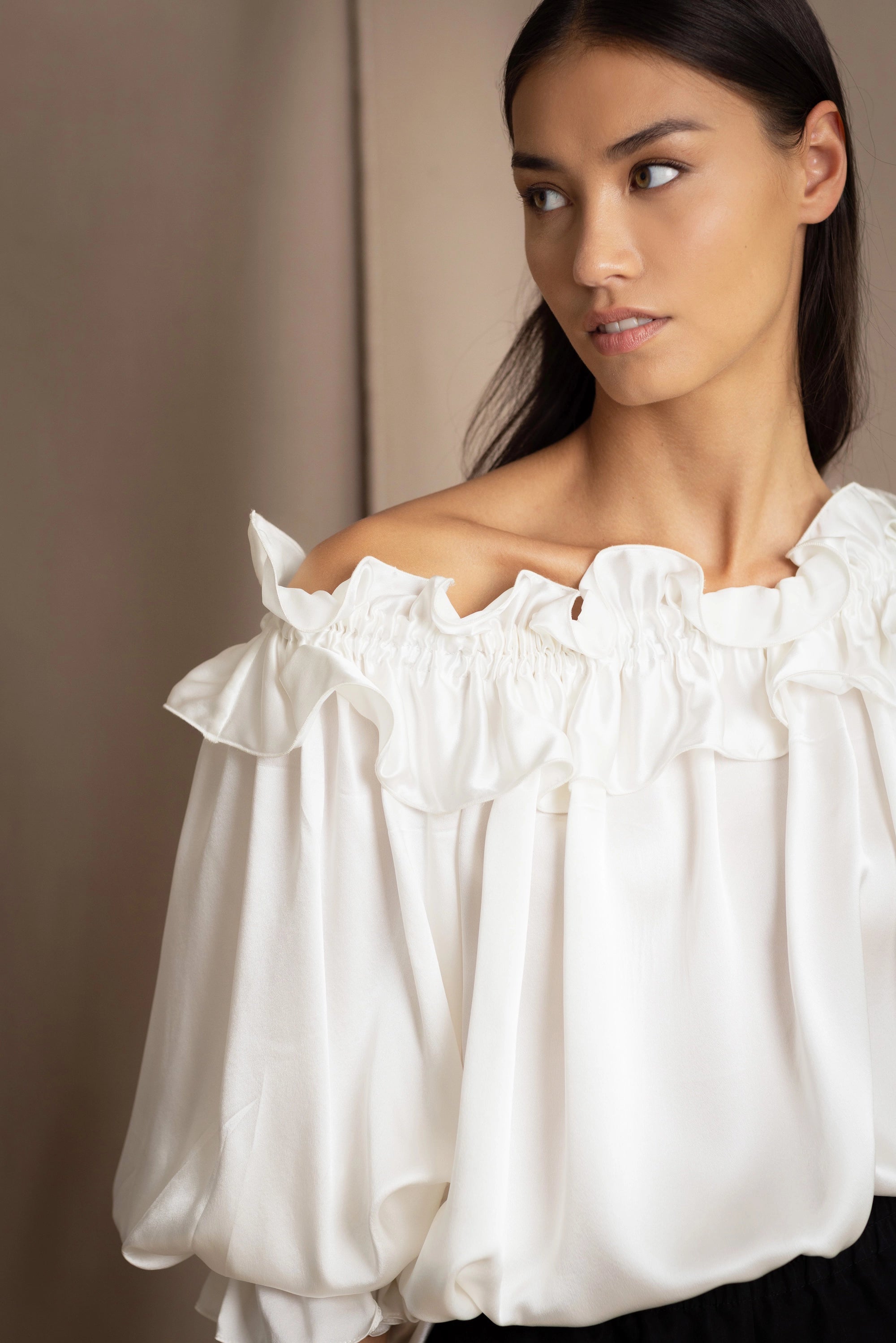 Woman wearing a white silk blouse with ruffled details