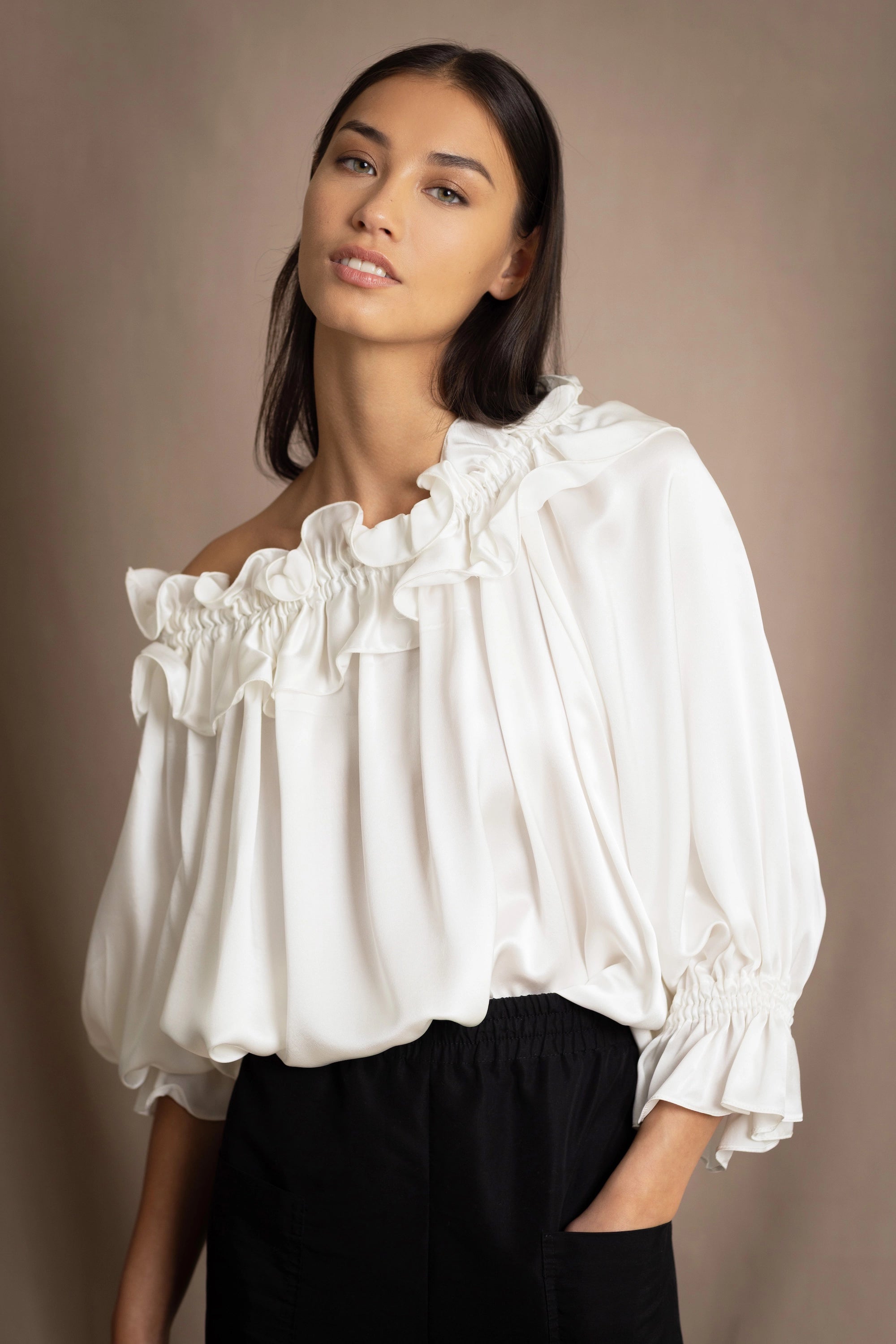 Woman wearing a white silk blouse with ruffled details