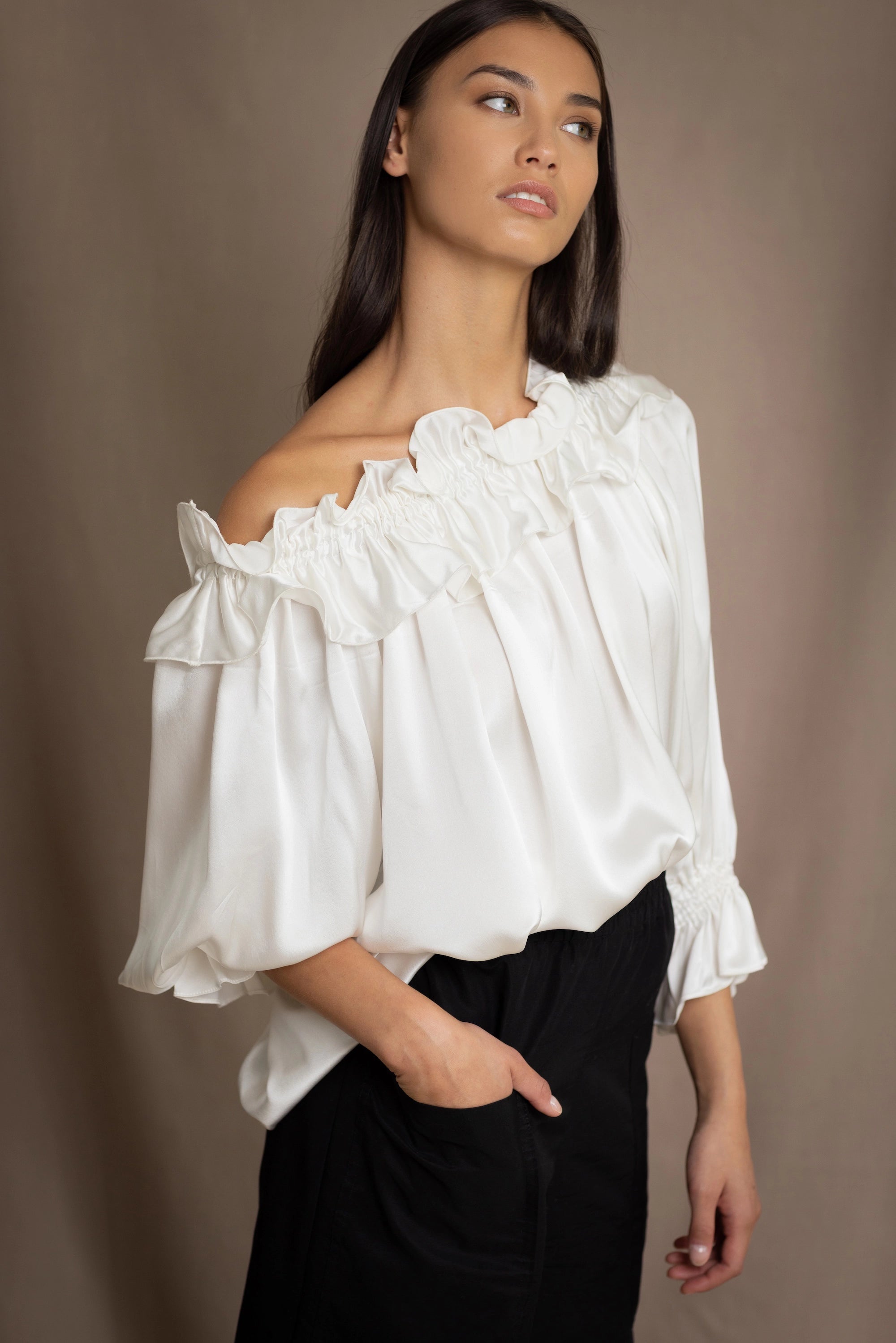 Woman wearing a white silk blouse with ruffled details