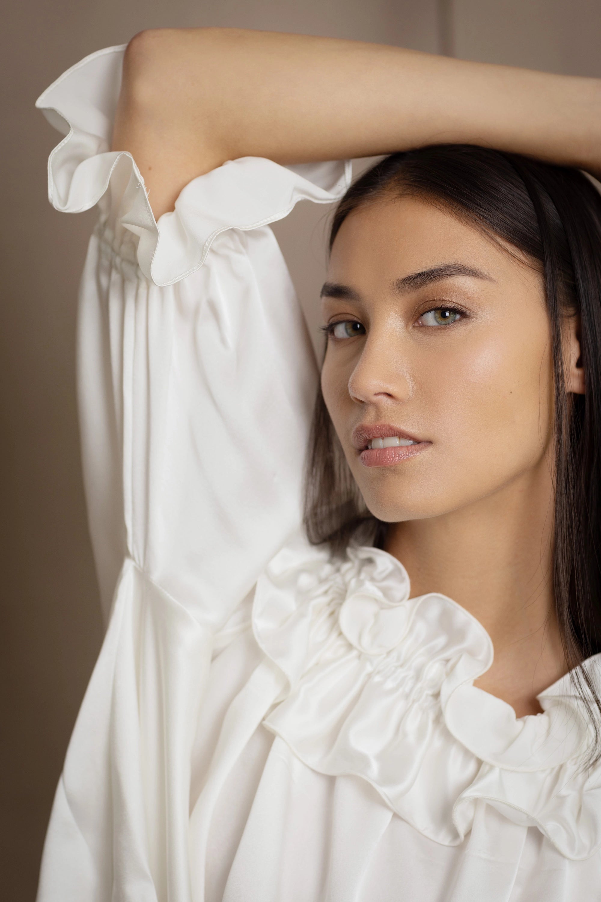 Woman wearing a white silk blouse with ruffled details