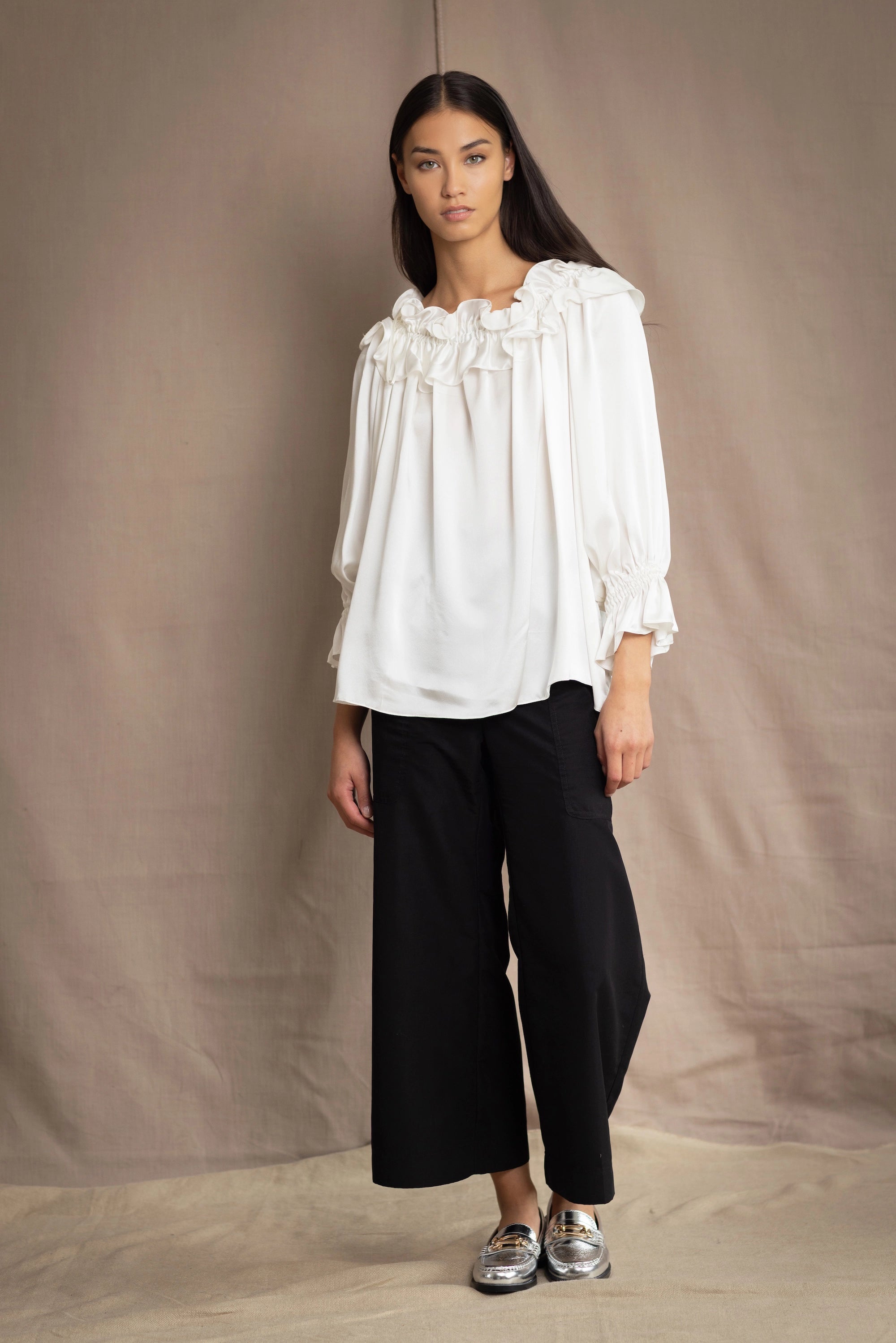 Woman wearing a white silk blouse with ruffled details
