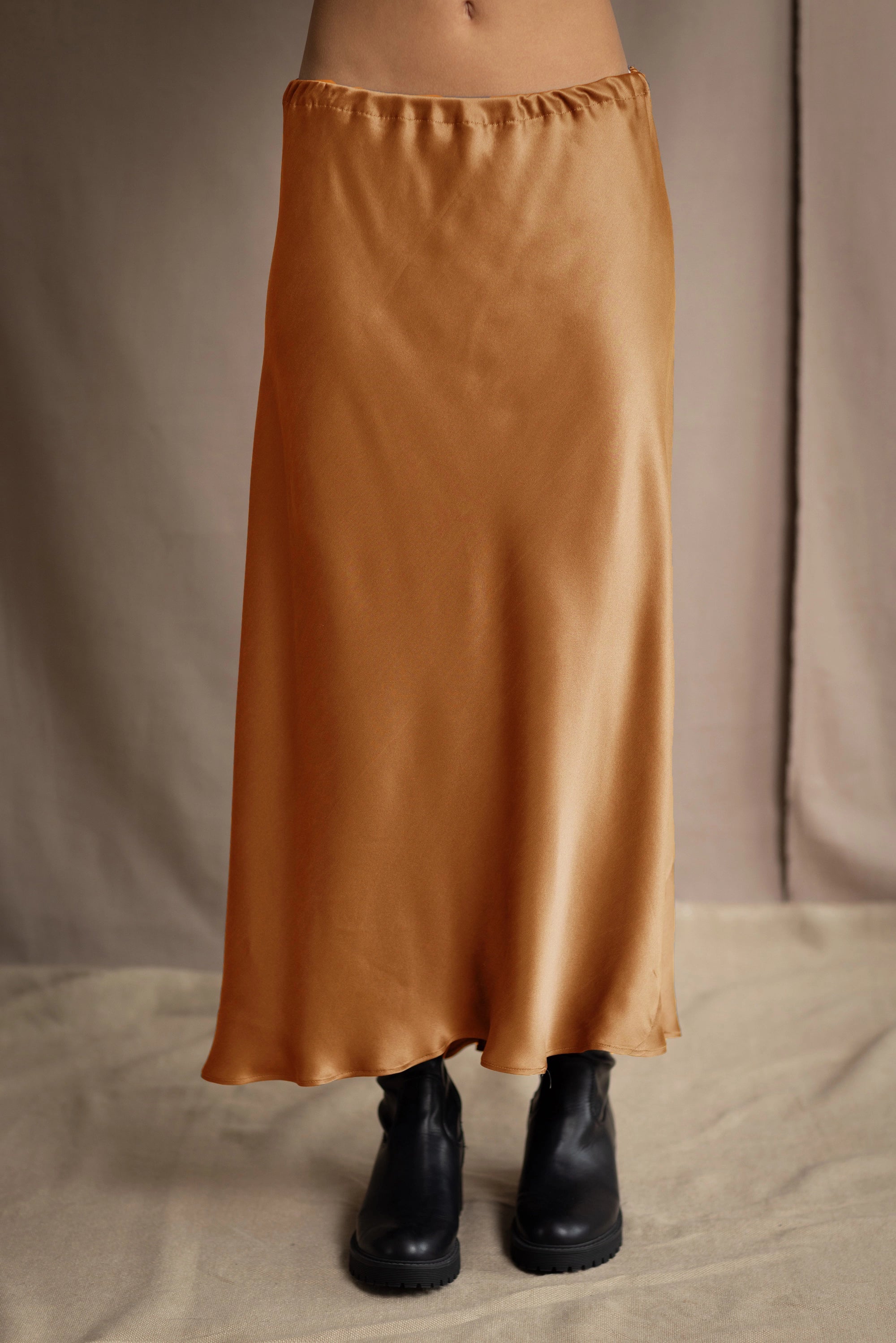 woman wearing a long bronze silk midi skirt with black boots