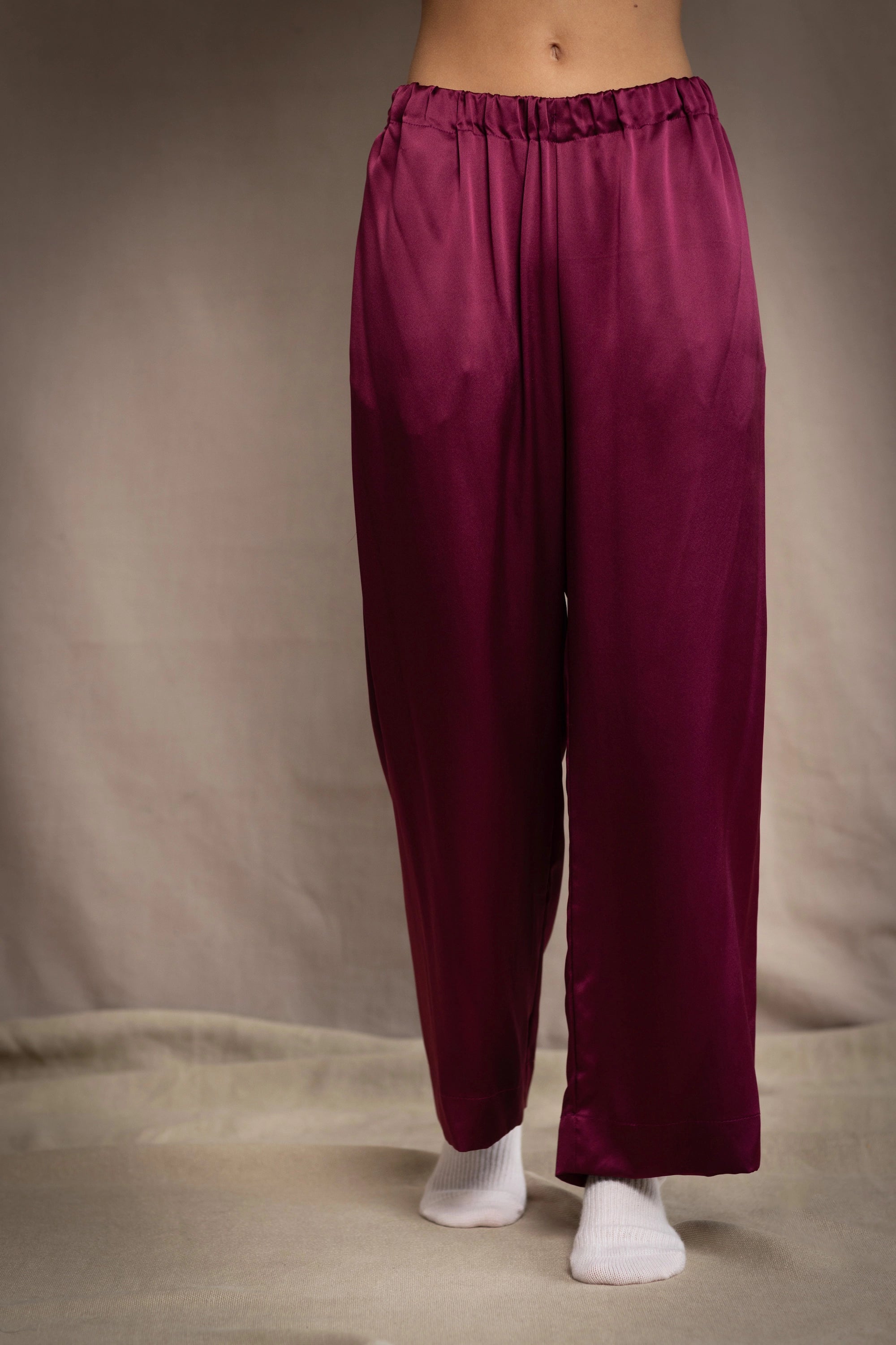 a woman wears burgundy silk trousers