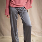 a woman wearing silk pants in a metallic gray pewter