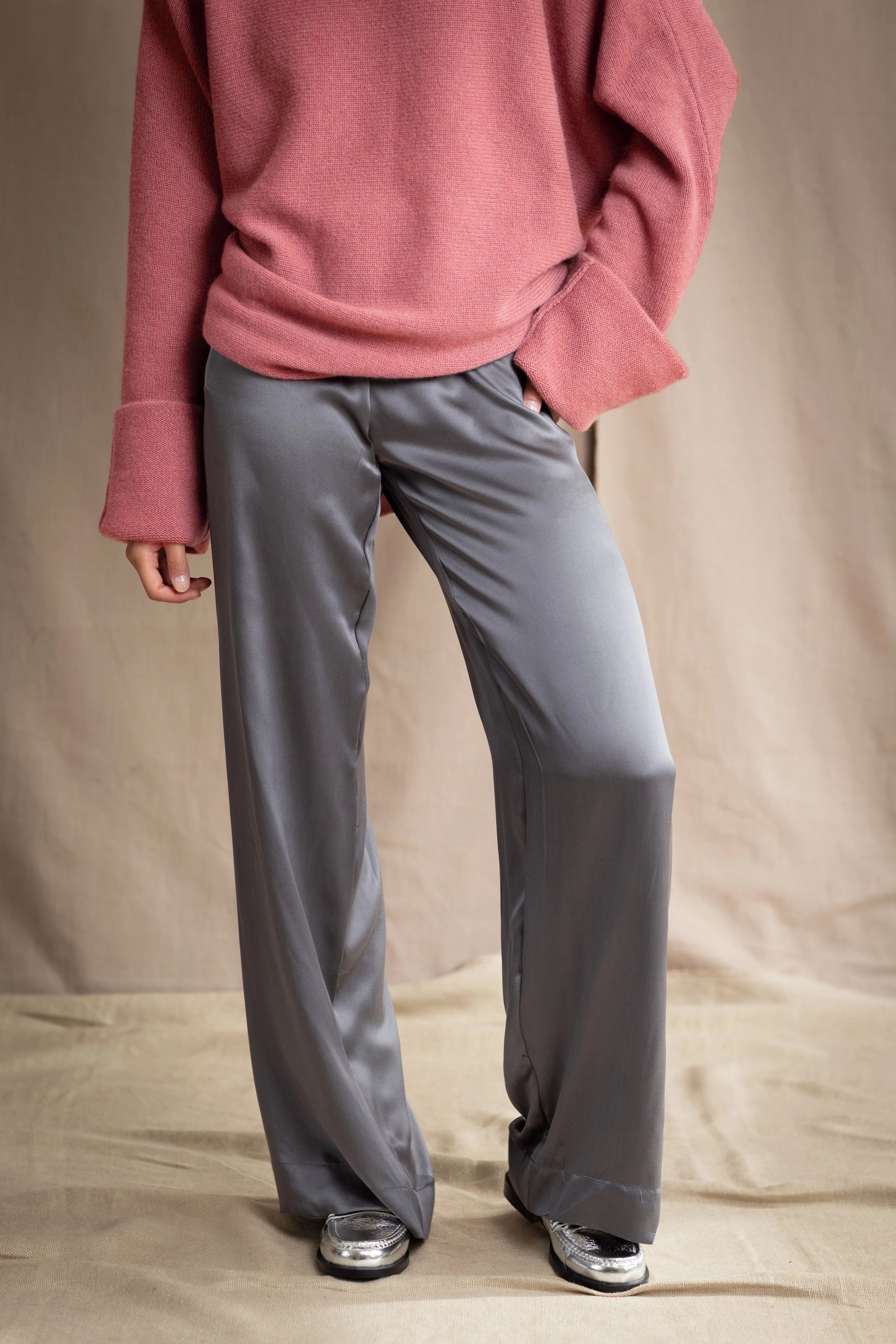 a woman wearing silk pants in a metallic gray pewter