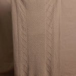 A lady wears a pure cashmere aran blanket in taupe