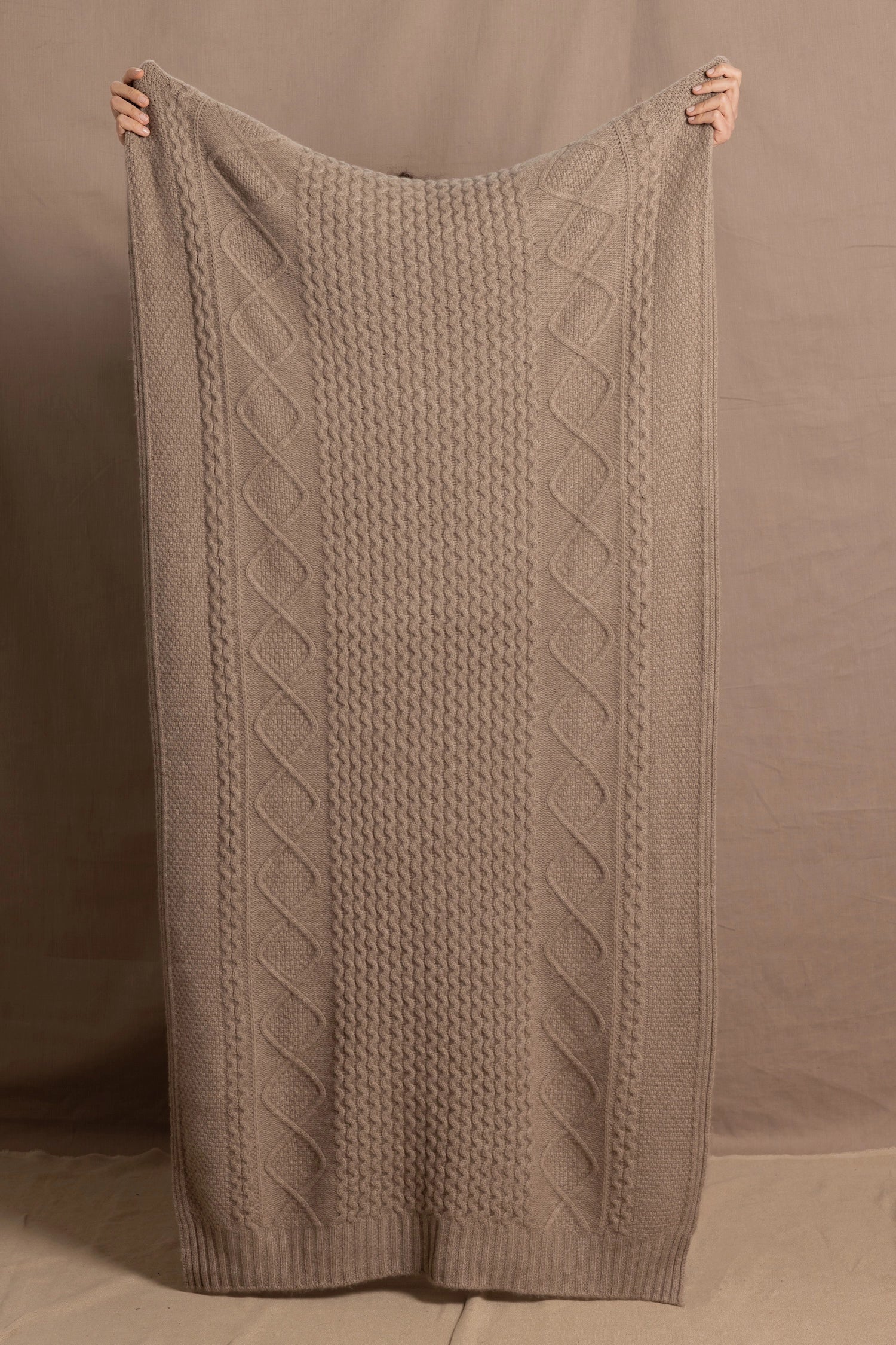 A lady wears a pure cashmere aran blanket in taupe