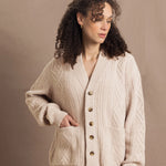 a woman wears a beige coloured cashmere aran cardigan sweater with horn buttons