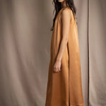 a woman wearing a bronze silk sleeveless dress