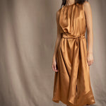 a woman wearing a bronze silk sleeveless dress