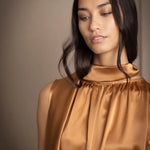 a woman wearing a bronze silk sleeveless dress