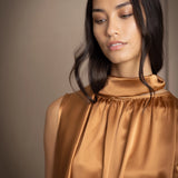 a woman wearing a bronze silk sleeveless dress