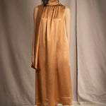 a woman wearing a bronze silk sleeveless dress
