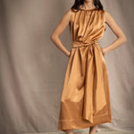 a woman wearing a bronze silk sleeveless dress