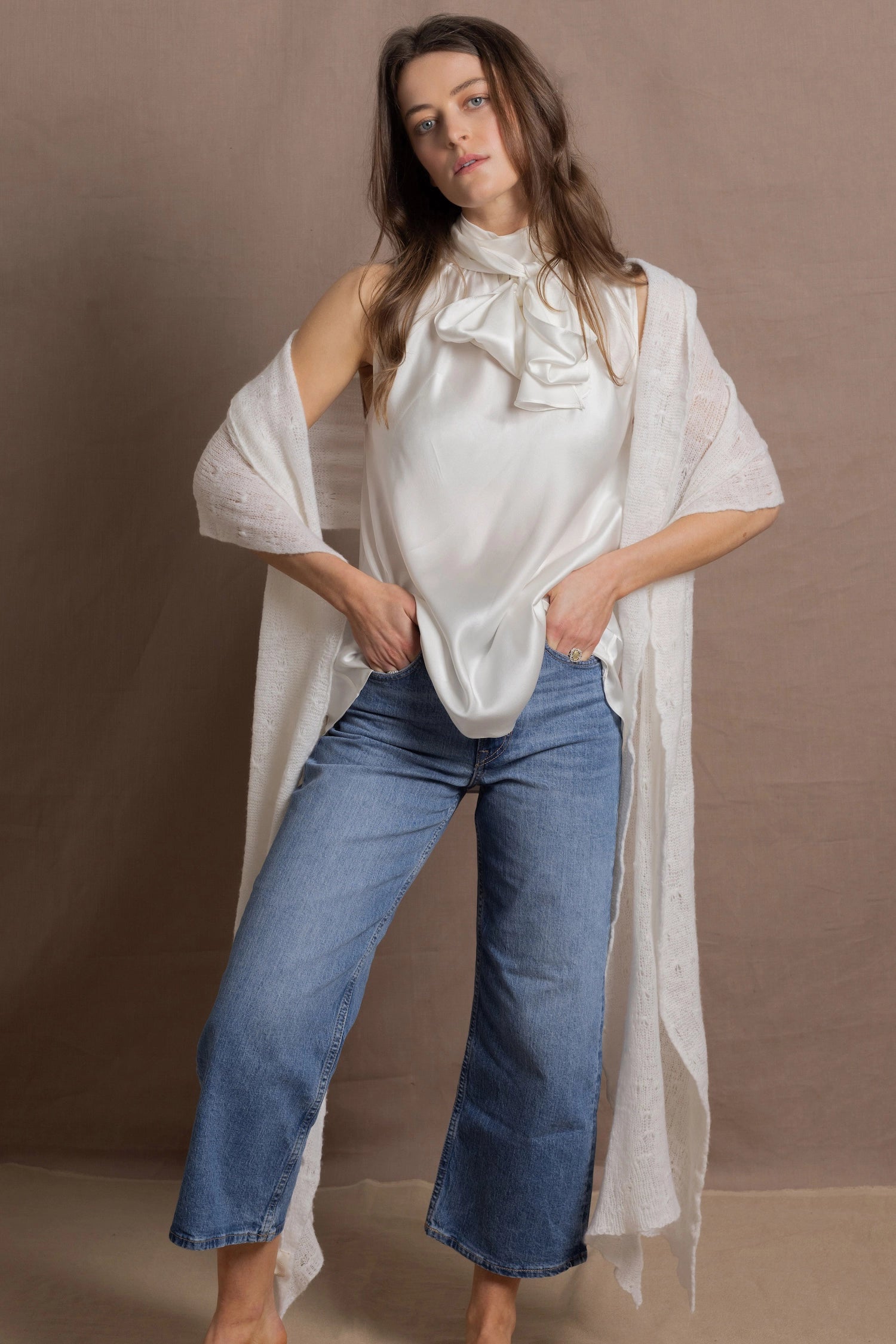 A woman wears a 100% silk pussybow sleeveless blouse in white with a pair of jeans and a matching cashmere lace shawl