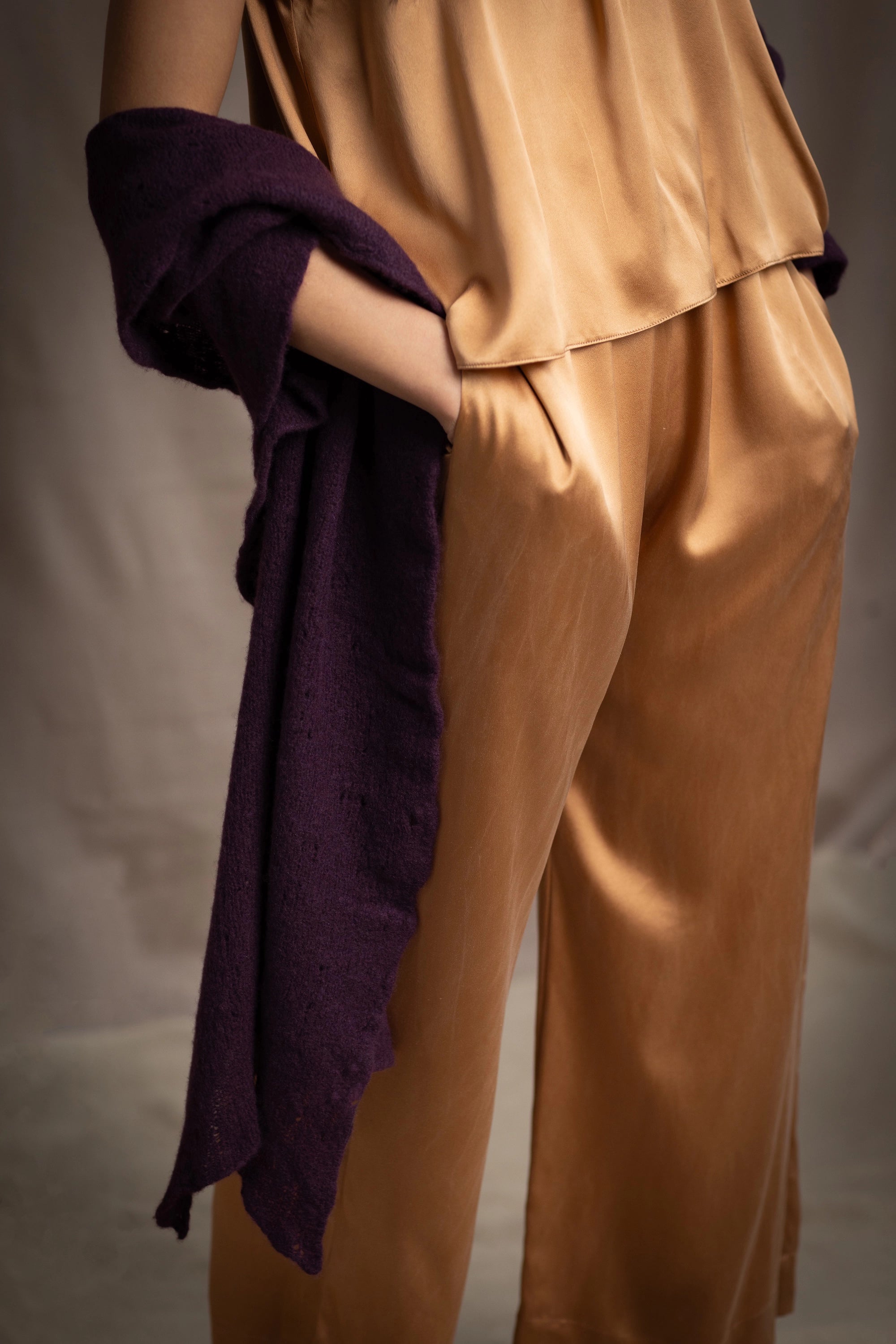 Woman wearing a dark purple cashmere lace wrap over bronze silk clothing