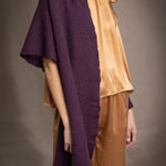 Woman wearing a dark purple cashmere lace wrap over bronze silk clothing