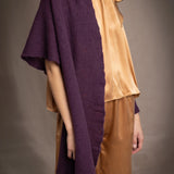 Woman wearing a dark purple cashmere lace wrap over bronze silk clothing
