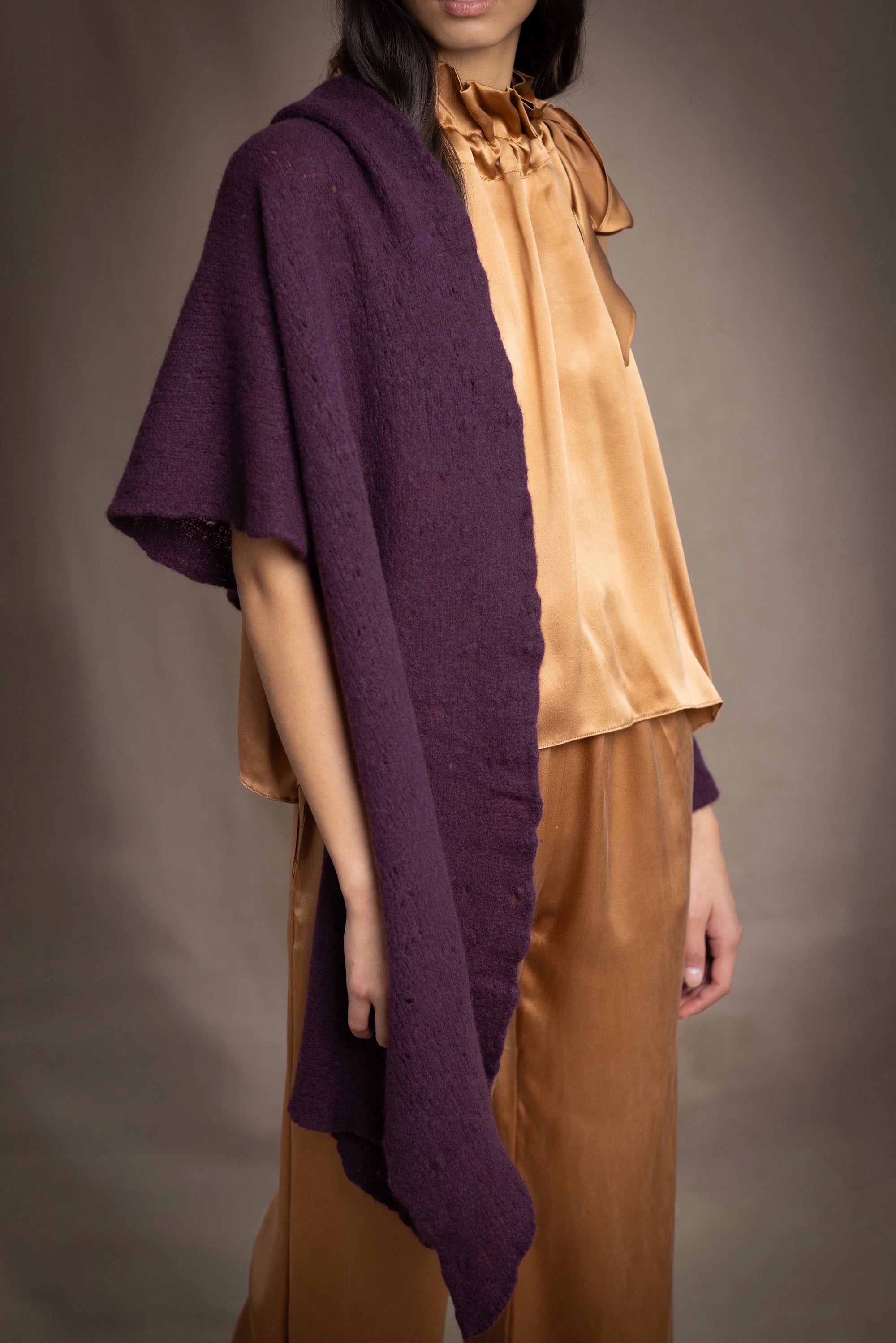 Woman wearing a dark purple cashmere lace wrap over bronze silk clothing
