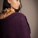 Woman wearing a dark purple cashmere lace wrap over bronze silk clothing