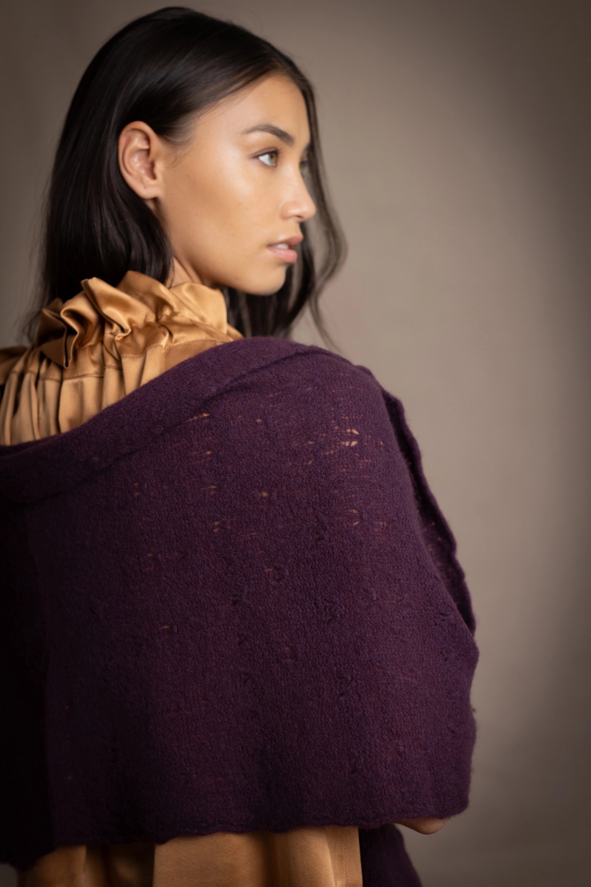 Woman wearing a dark purple cashmere lace wrap over bronze silk clothing