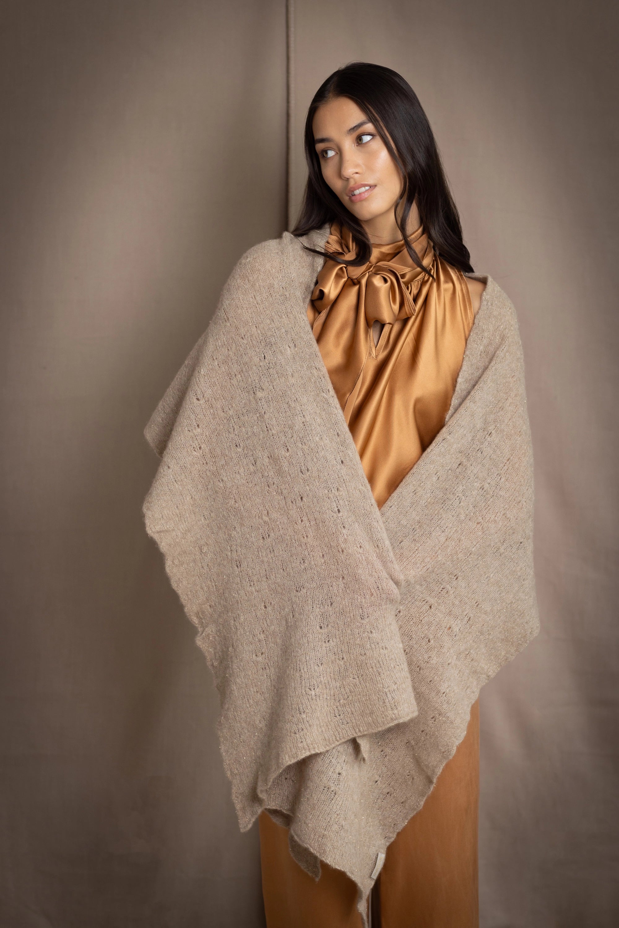 Woman wearing a beige and metallic gold cashmere lace wrap over bronze silk clothing