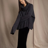 woman wearing an oversized cashmere sweater with cowl neck in black with silver metallic lurex thread over silk velvet skirt in black