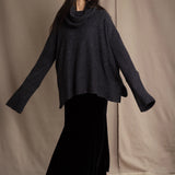 woman wearing an oversized cashmere sweater with cowl neck in black with silver metallic lurex thread over silk velvet skirt in black