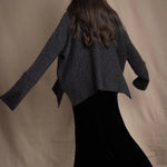 woman wearing an oversized cashmere sweater with cowl neck in black with silver metallic lurex thread over silk velvet skirt in black