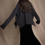 woman wearing an oversized cashmere sweater with cowl neck in black with silver metallic lurex thread over silk velvet skirt in black