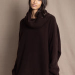 woman wearing an oversized cashmere sweater with cowl neck in dark brown over  pale pink tulle skirt