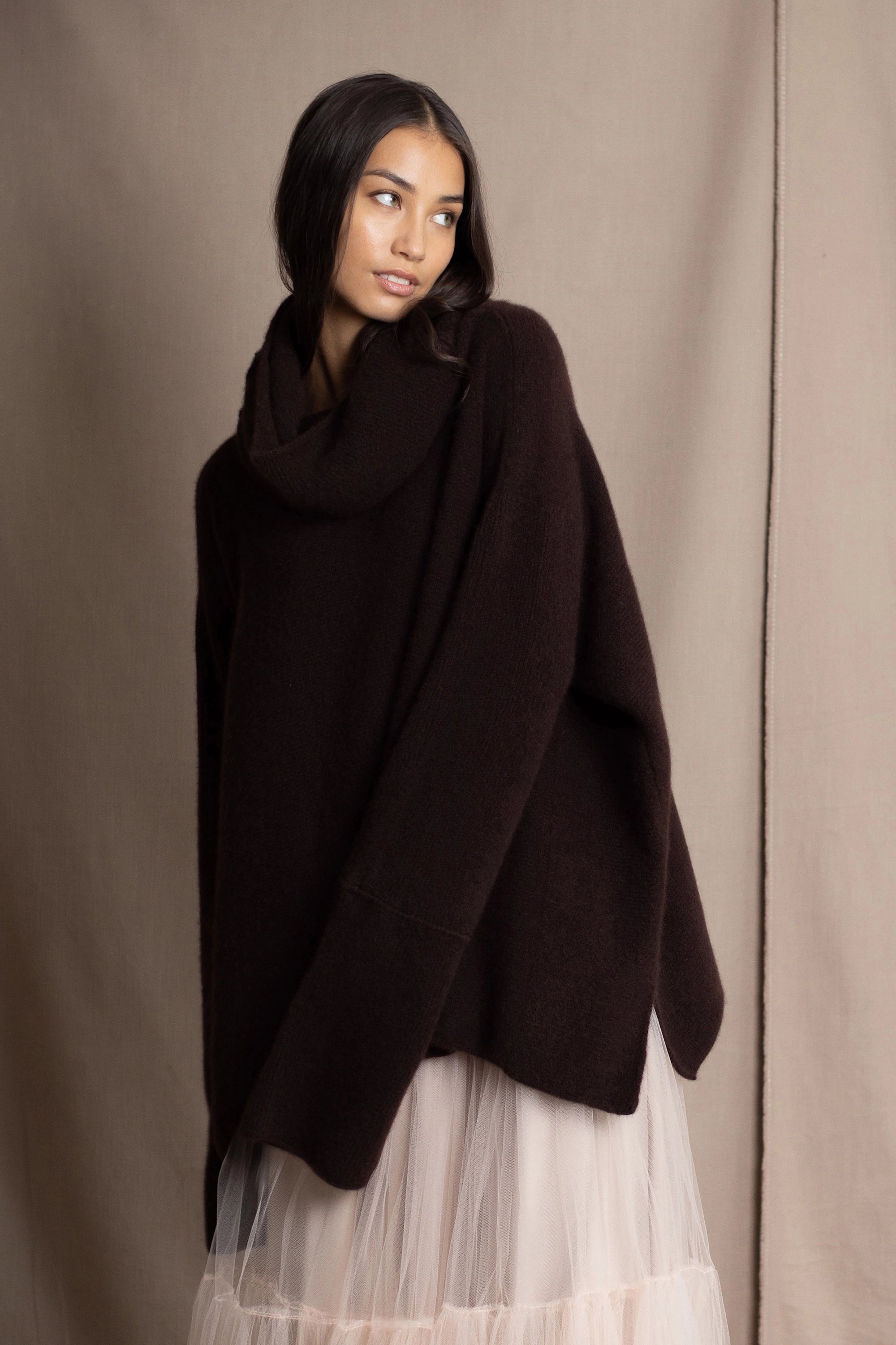 woman wearing an oversized cashmere sweater with cowl neck in dark brown over  pale pink tulle skirt