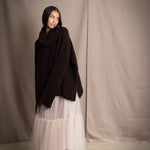 woman wearing an oversized cashmere sweater with cowl neck in dark brown over  pale pink tulle skirt