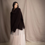 woman wearing an oversized cashmere sweater with cowl neck in dark brown over  pale pink tulle skirt