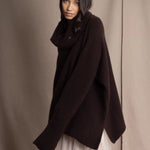 woman wearing an oversized cashmere sweater with cowl neck in dark brown over  pale pink tulle skirt