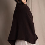 woman wearing an oversized cashmere sweater with cowl neck in dark brown over  pale pink tulle skirt