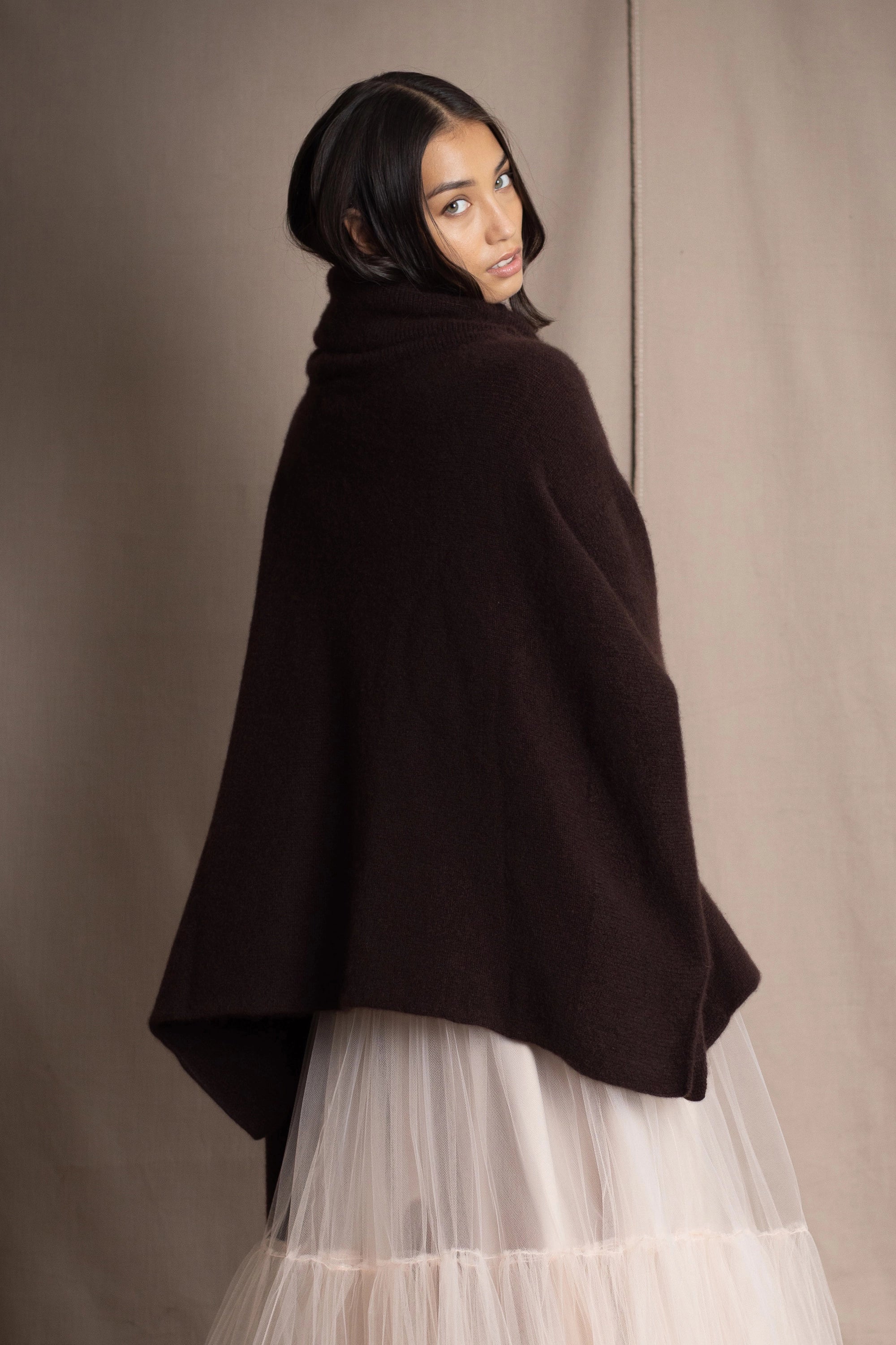 woman wearing an oversized cashmere sweater with cowl neck in dark brown over  pale pink tulle skirt