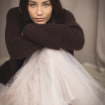 woman wearing an oversized cashmere sweater with cowl neck in dark brown over  pale pink tulle skirt