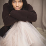 woman wearing an oversized cashmere sweater with cowl neck in dark brown over  pale pink tulle skirt