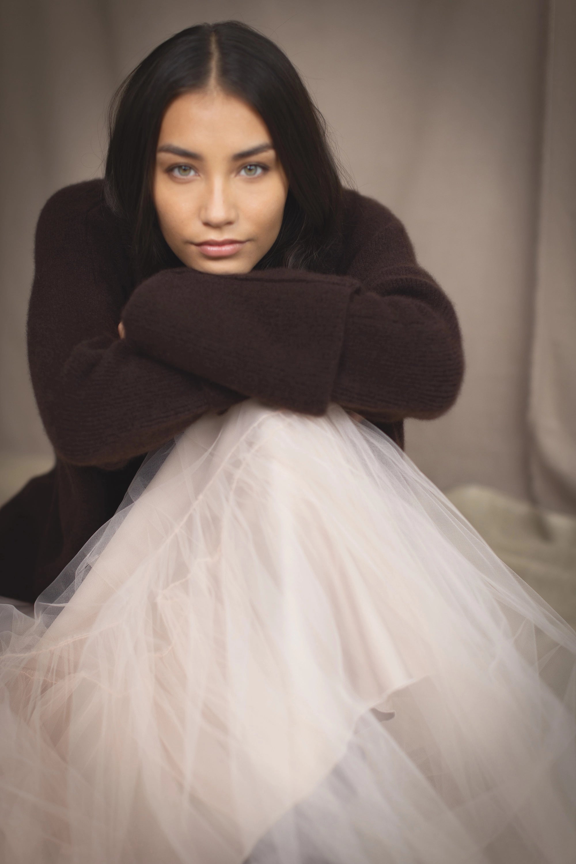 woman wearing an oversized cashmere sweater with cowl neck in dark brown over  pale pink tulle skirt
