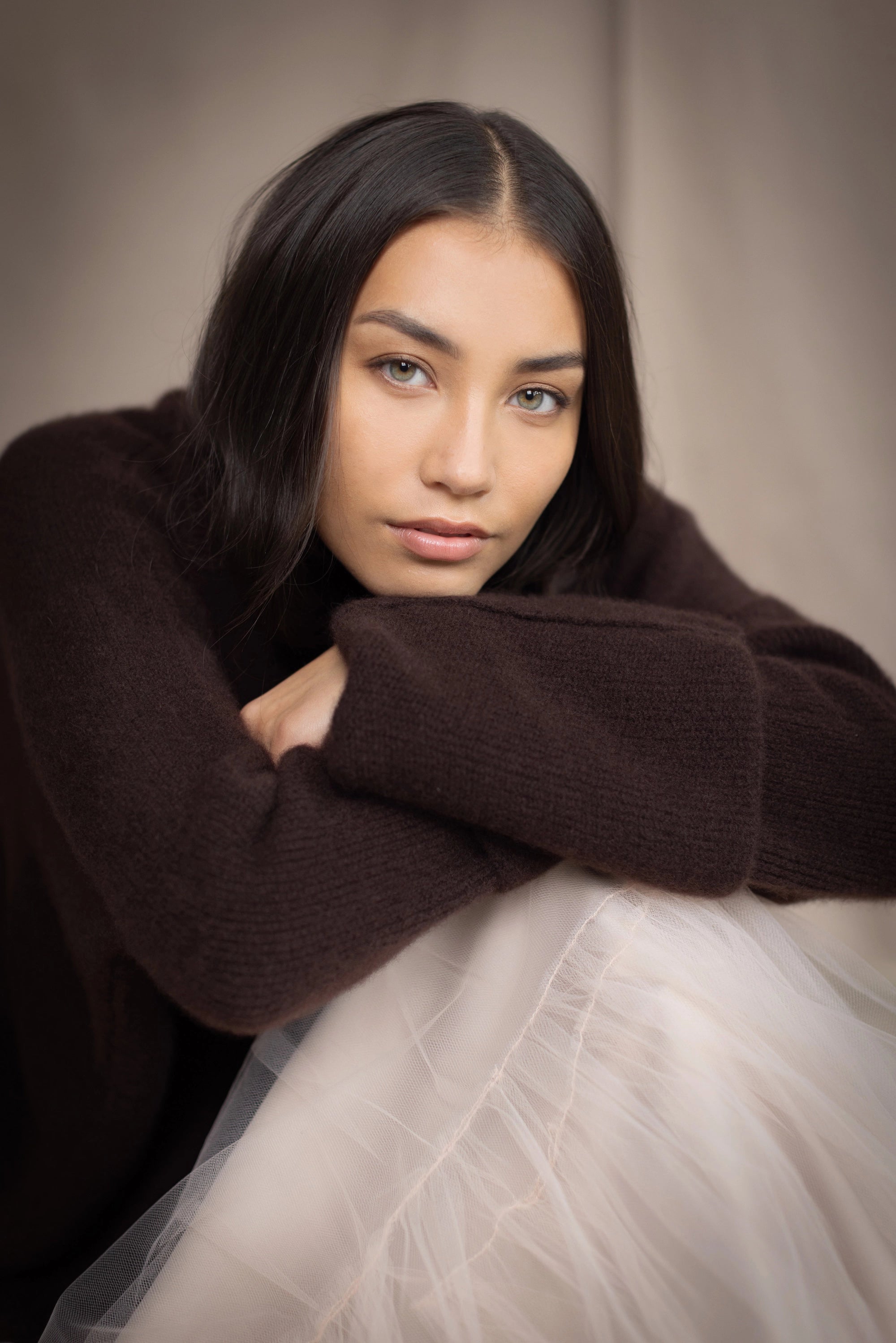 woman wearing an oversized cashmere sweater with cowl neck in dark brown over  pale pink tulle skirt